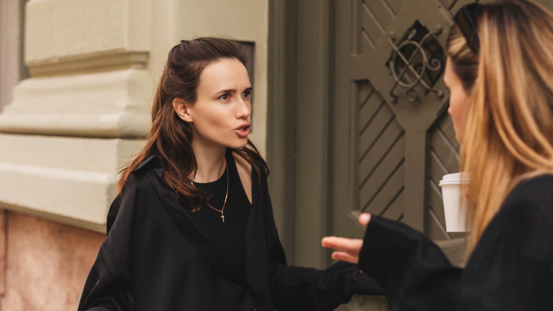 two women in black arguing outside as chaos shows up out of nowhere