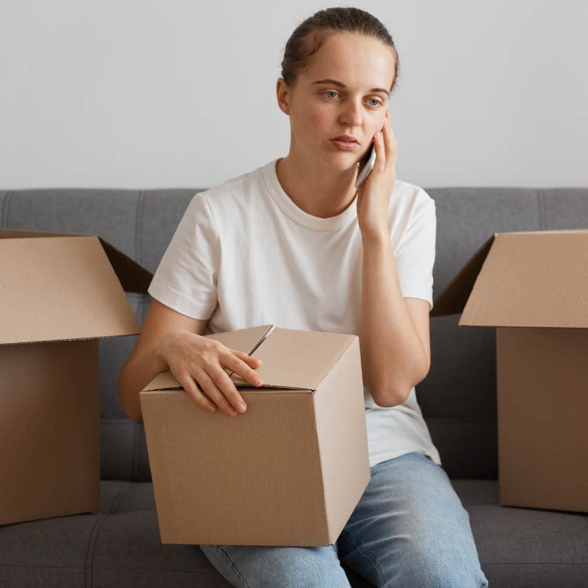 Woman sitting around unopened boxes everywhere.