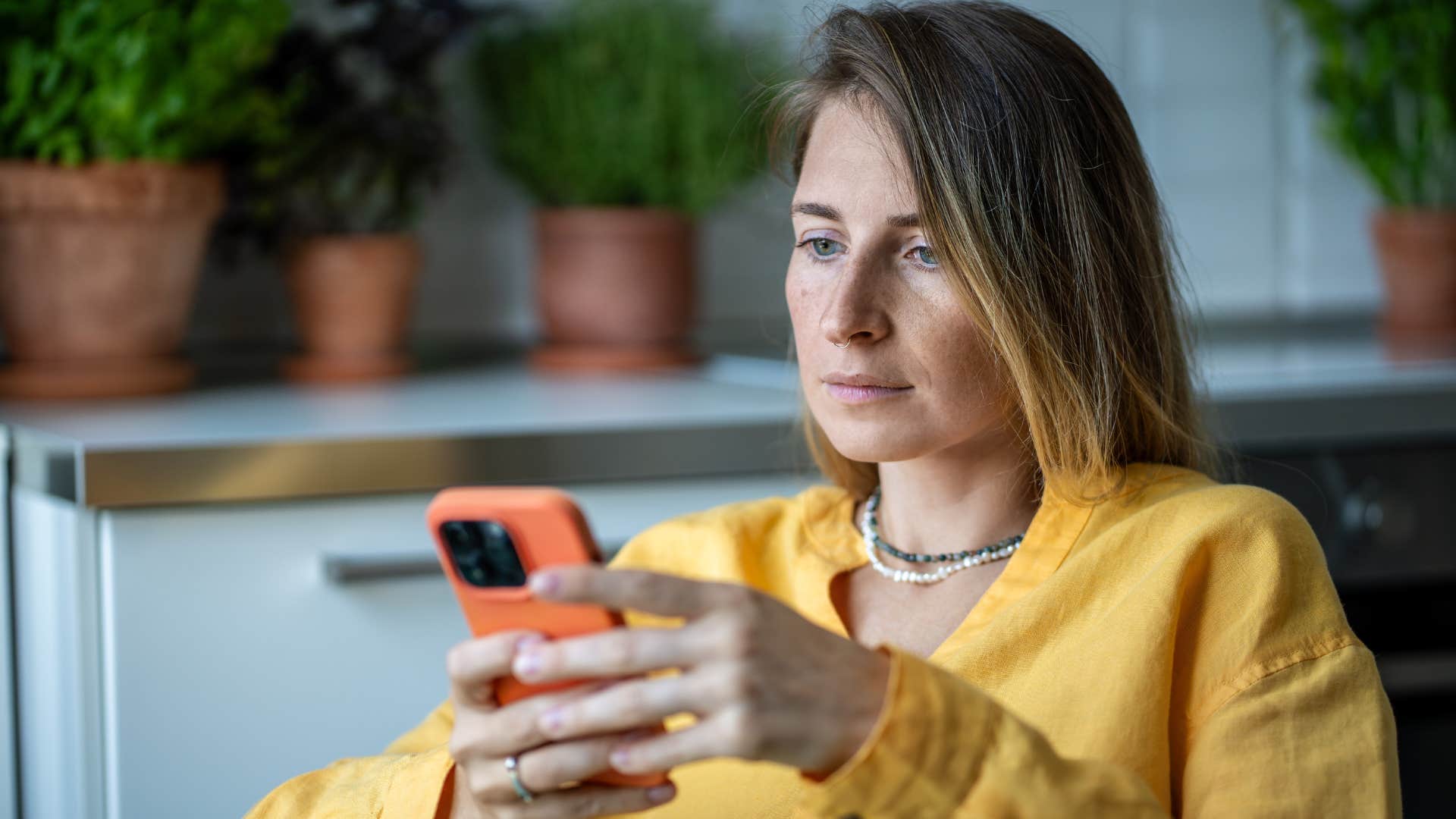 Woman with unprocessed grief and unresolved trauma scrolling on her phone.