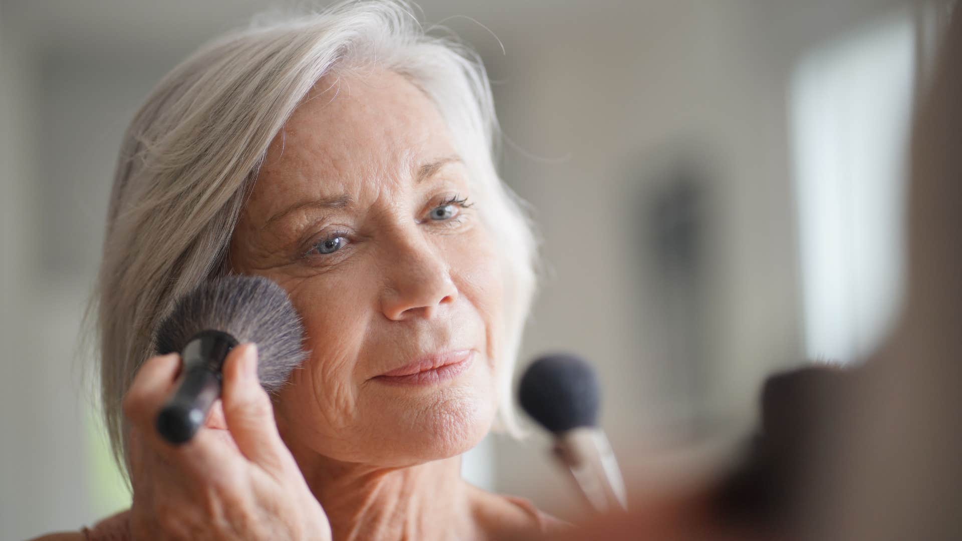 older woman putting on makeup