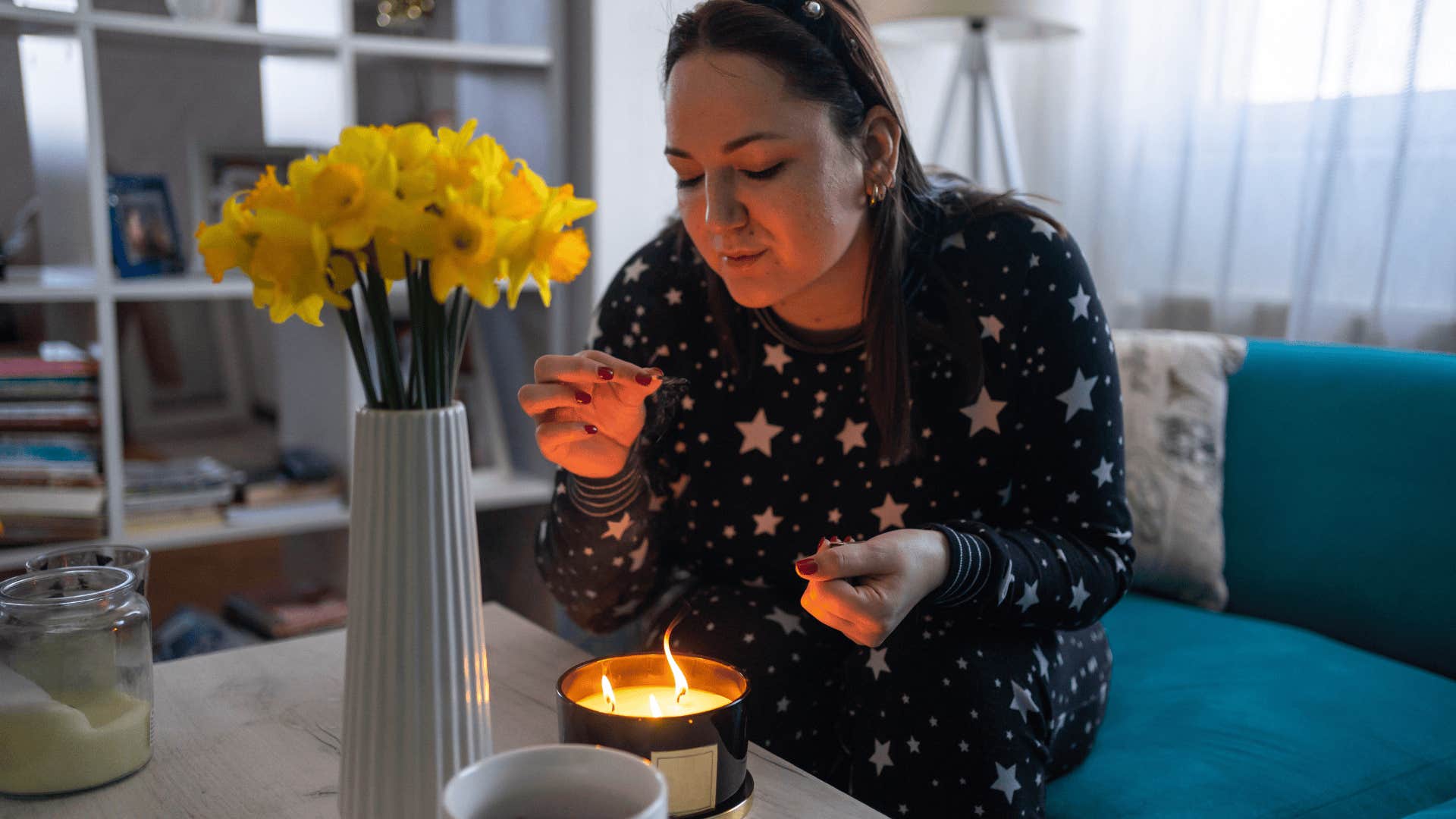 woman lighting a candle to stay calm and balanced