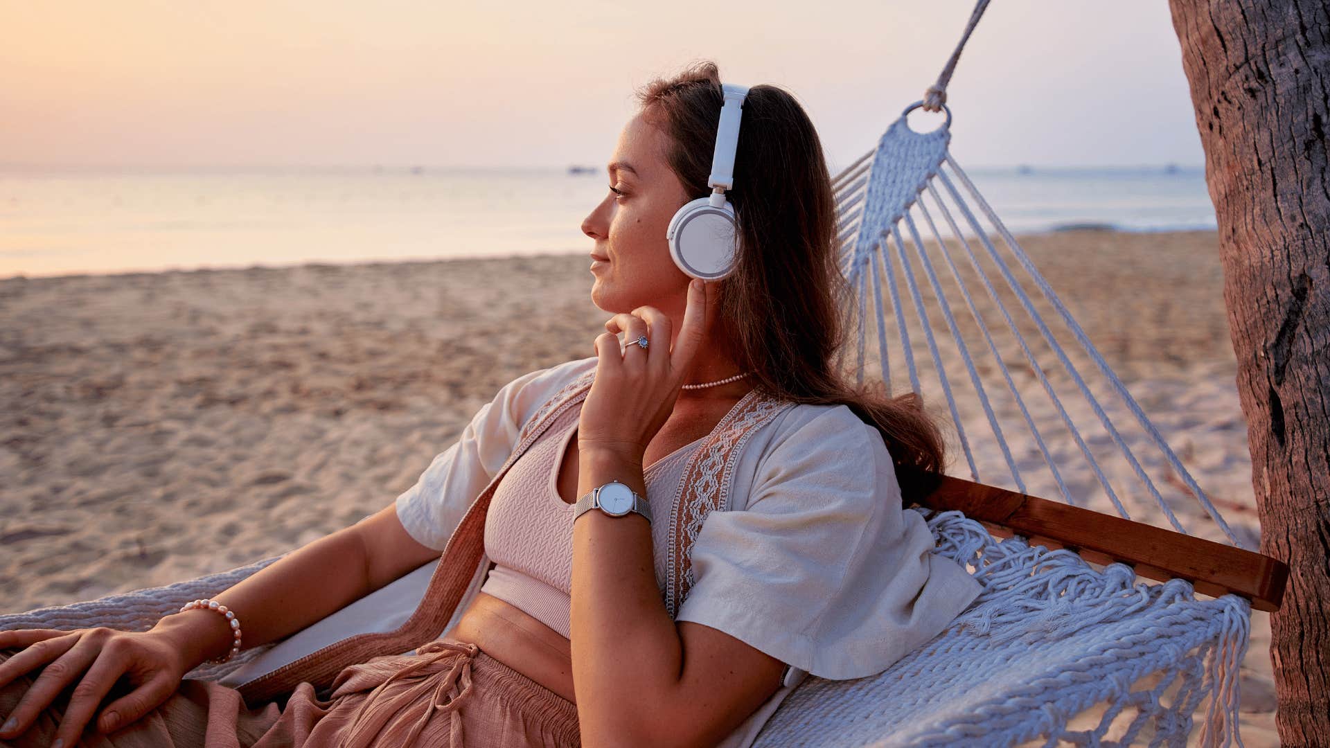 calm and relaxed woman listens to music on the beach