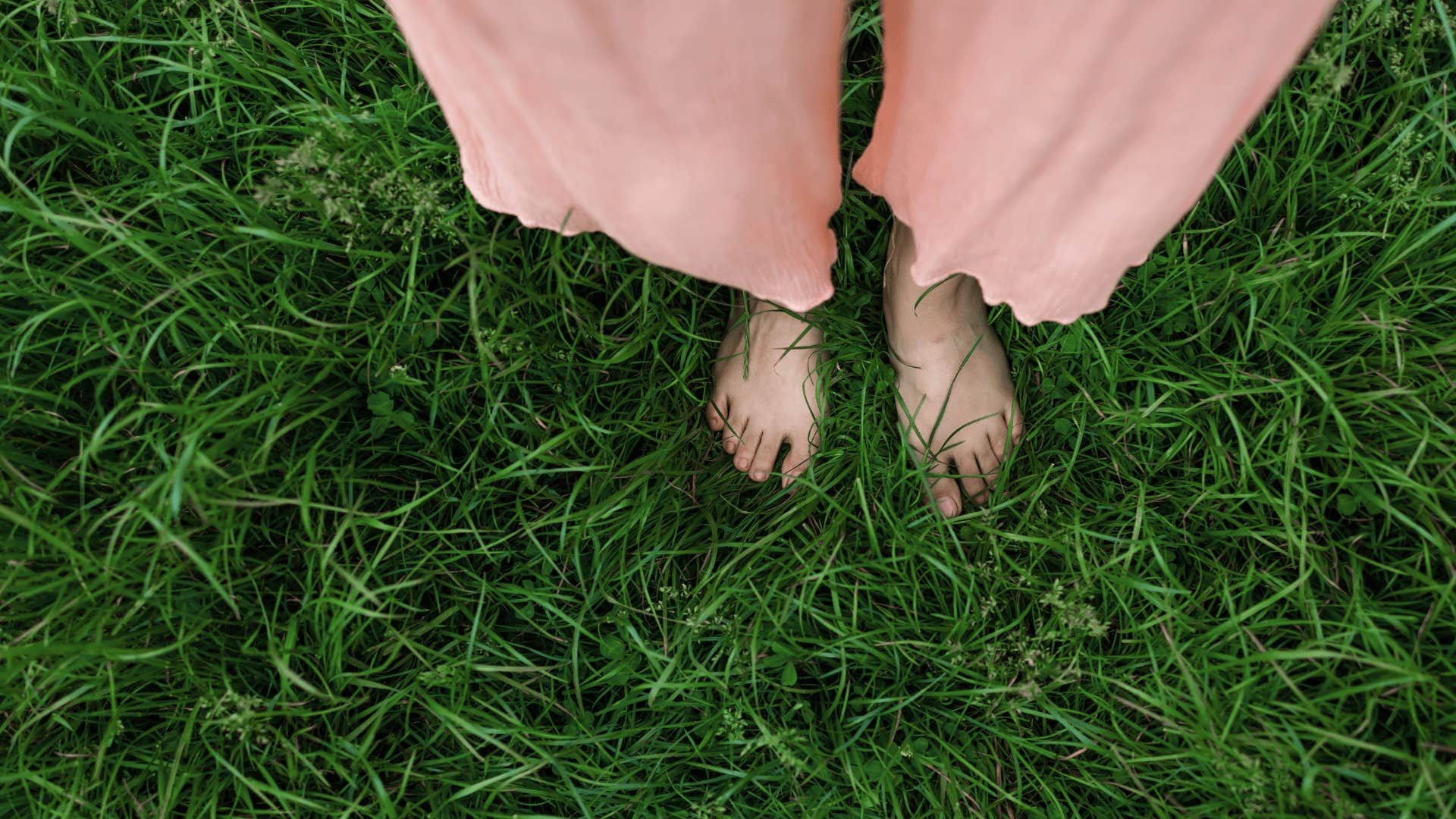 woman touching her feet to the grass to stay calm, balanced and centered