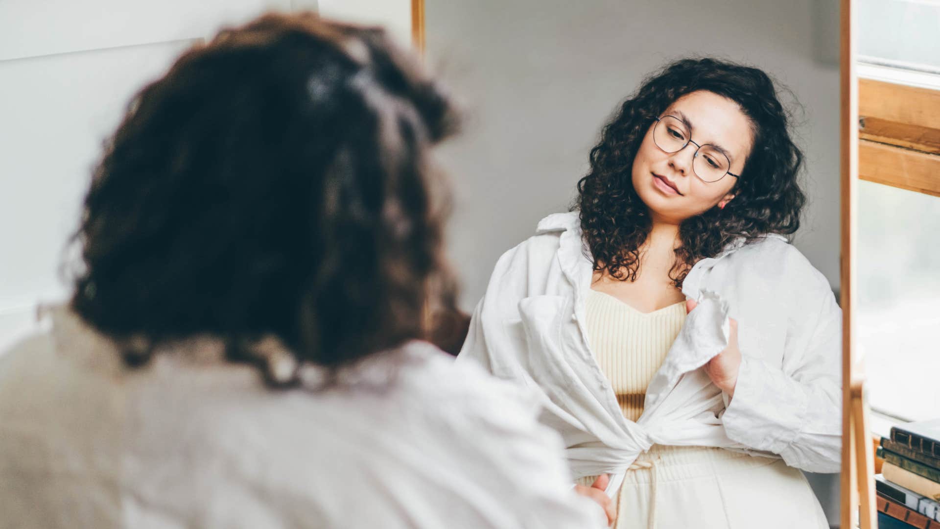 woman trying on oversized clothing in the mirror