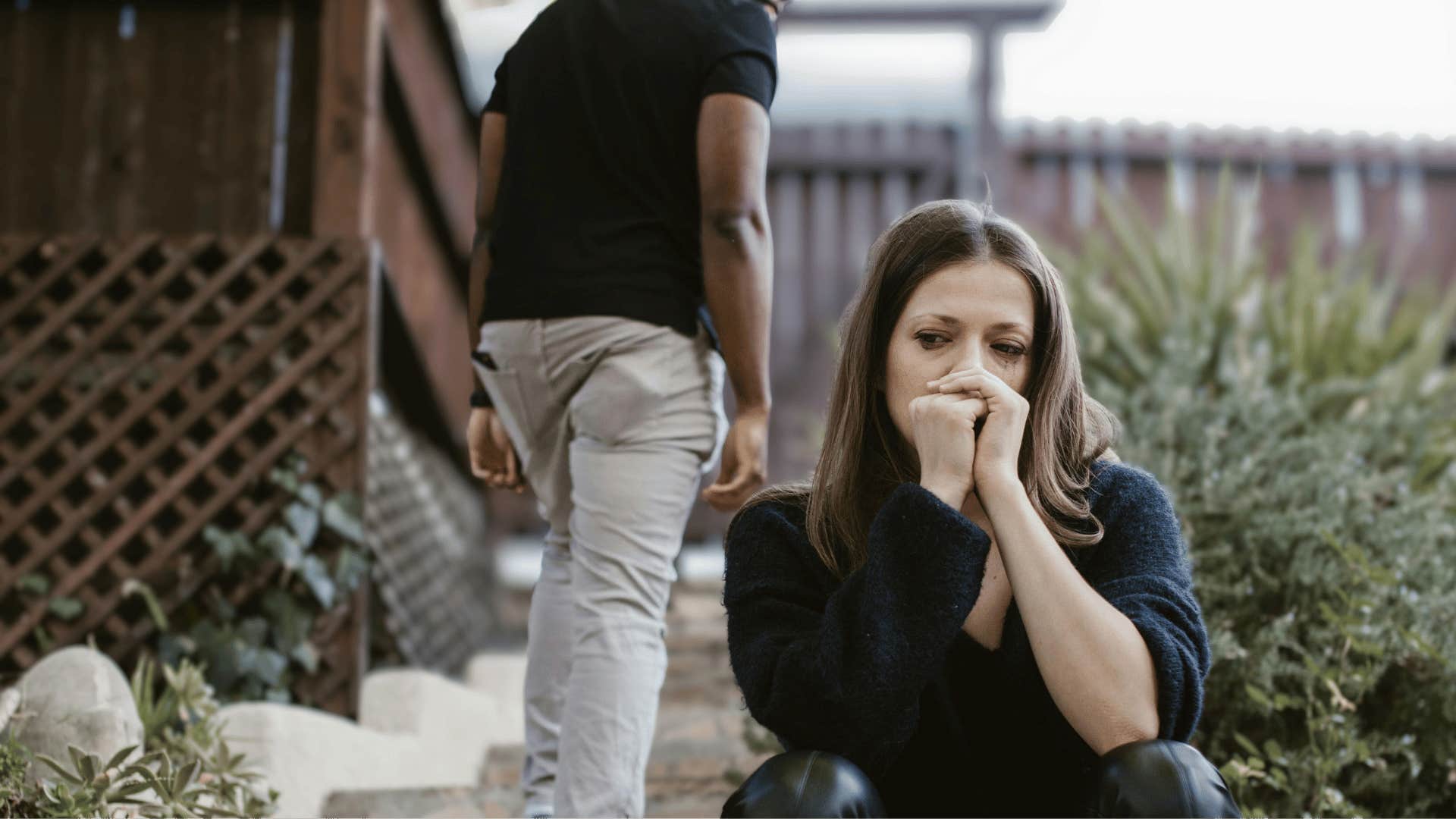 man walking away from crying woman on stairs