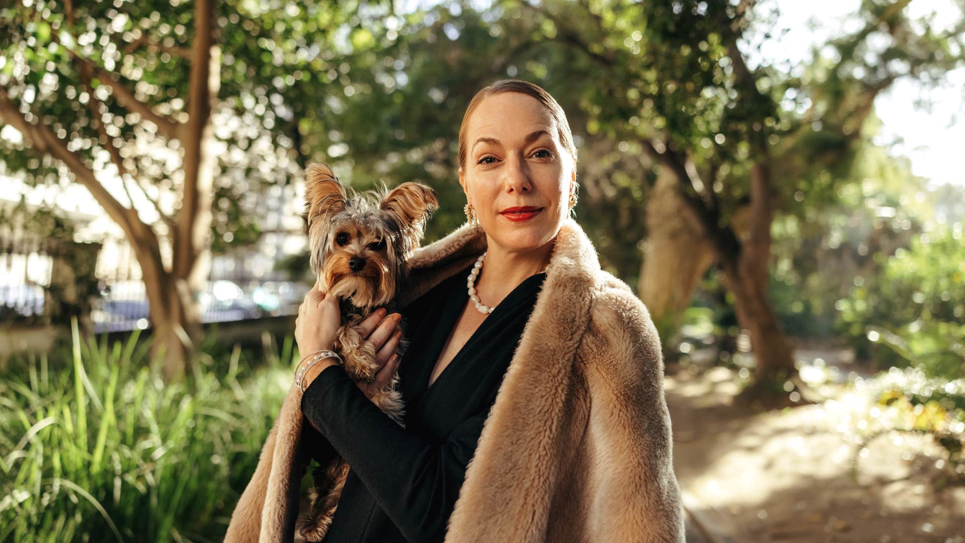 wealthy woman with dog walking around outside in the park