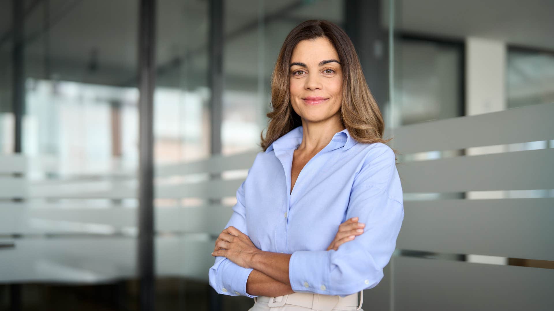 woman in blue crossing arms confidently as she dresses simply but well fitted