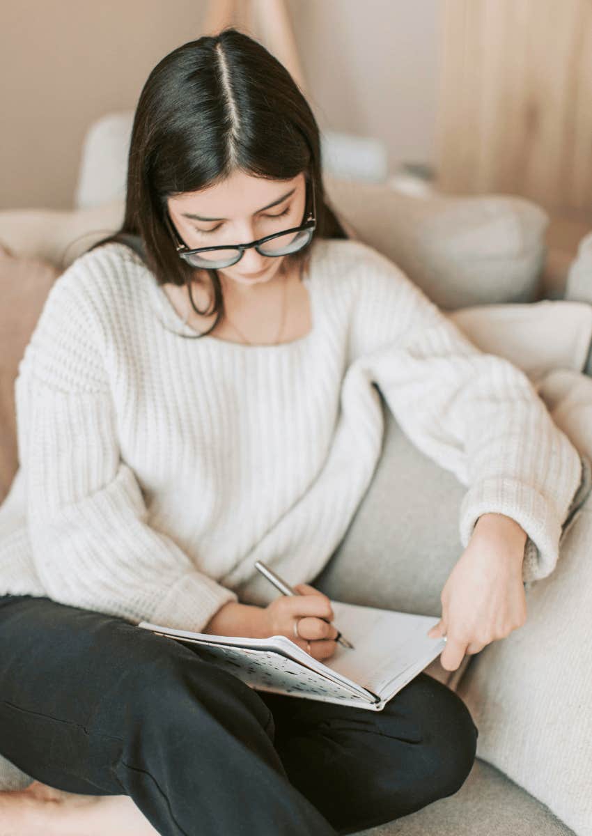 young woman in glasses journaling